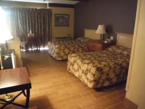 a hotel room with two beds and a table at Budgetel Inn & Suites Hotel in Grand Rapids