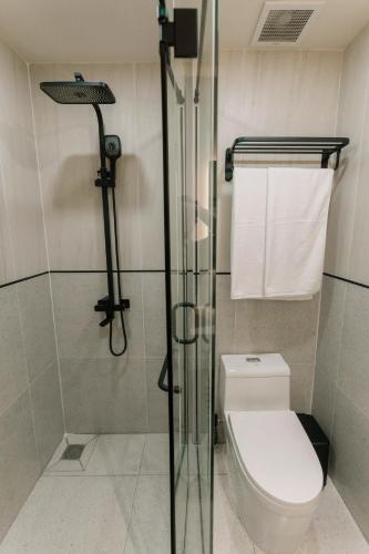 a bathroom with a toilet and a glass shower at EL Where Hotel in Ho Chi Minh City