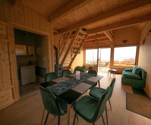 a dining room with a table and green chairs at Domki w Beskidach- Agroturystyka" Babiogórski pejzaż" in Pewel Wielka