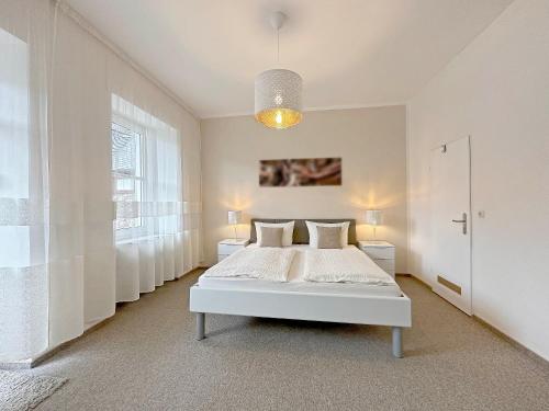 a white bedroom with a bed and a window at Gast und Weinhof Beim Schneemann in Valwig