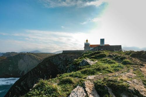 a lighthouse on top of a hill with the ocean at La Casona de Faedo Pensión in Faedo