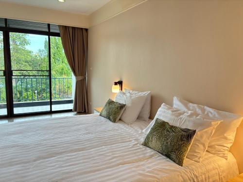 a bedroom with a bed with pillows and a window at Eco Hotel by Thammasat in Bang Lamung