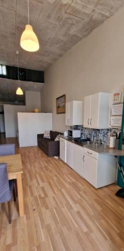 a kitchen with white cabinets and a wooden floor at Reykjanes Apartments in Grindavík