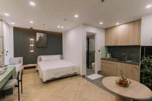 a bedroom with a bed and a table and a kitchen at EL Where Hotel in Ho Chi Minh City