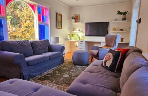 a living room with blue couches and a tv at Chateau By The Bay in Kingston Beach