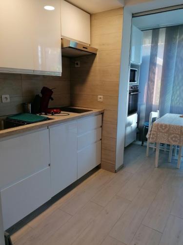 une cuisine avec des armoires blanches et une table dans une pièce dans l'établissement charming studio Carro-25 m2 - garden - close to beaches, à Martigues