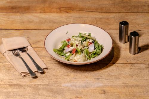a white plate of salad on a wooden table at Stay Studio Hotel & Residences in Gurgaon