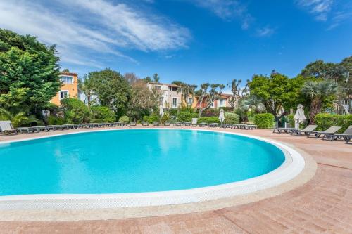 a swimming pool with chairs and a house in the background at Résidence Pierre & Vacances le Hameau de la Pinède in Hyères
