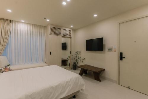 a bedroom with a white bed and a television at EL Where Hotel in Ho Chi Minh City
