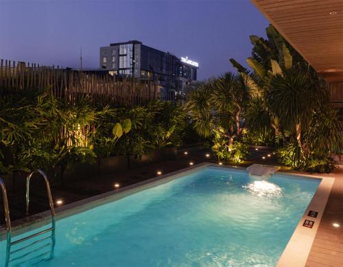 einem großen Pool mit Palmen und einem Gebäude in der Unterkunft M Village Hotel Premier Thi Sách in Ho-Chi-Minh-Stadt