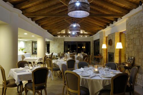 a restaurant with white tables and chairs and a chandelier at Styga Mountain Resort in Zarouchla