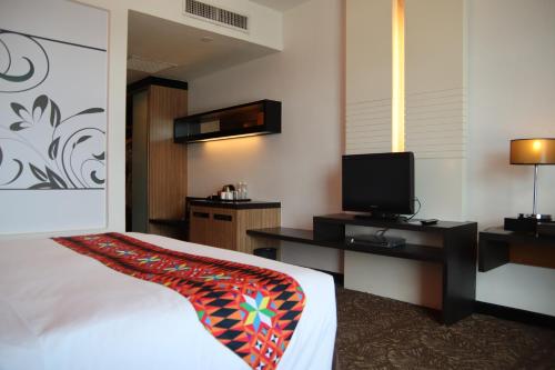 a hotel room with a bed and a flat screen tv at The Klagan Hotel in Kota Kinabalu