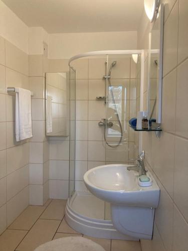 a white bathroom with a sink and a shower at Vila Carpatina in Breaza
