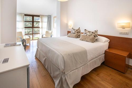 a white bedroom with a large white bed with pillows at Hotel Hurdes Reales in Las Mestas