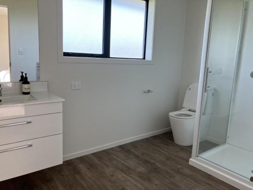 a white bathroom with a toilet and a window at 3-Bedroom Retreat in Mount Somers in Mount Somers