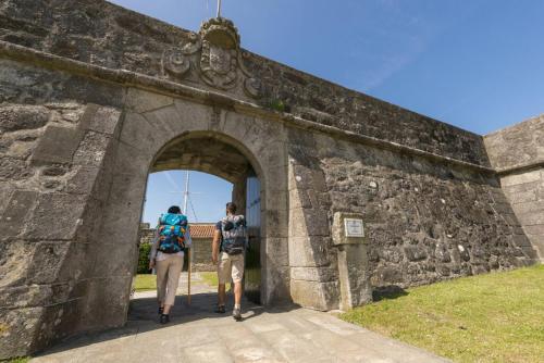 two people walking through an arch in a stone wall at Rooms in Casa da Foz do Rio in Caminha