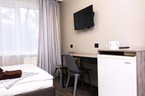 a hotel room with a desk and a bed and a tv at Hotel Tahar in Almaty