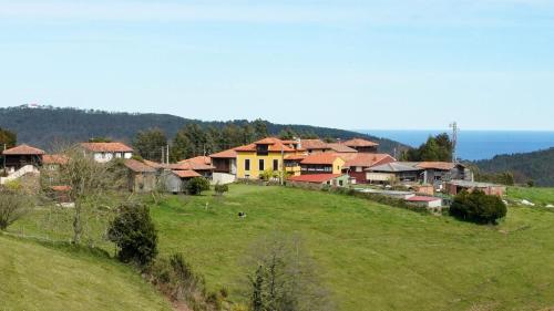 a group of houses on a hill with a green field at La Casona de Faedo Pensión in Faedo