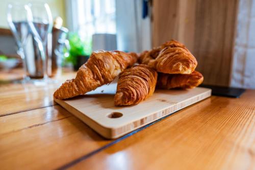 ein Stapel Croissants auf einem Schneidebrett auf einem Tisch in der Unterkunft Taper House - Cosy Medieval Cottage in Kersey