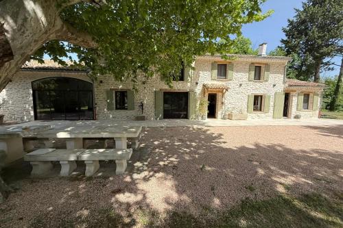 une maison en pierre avec un banc devant elle dans l'établissement Superb Mas provençal - swimming pool - tennis - park, à LʼIsle-sur-la-Sorgue