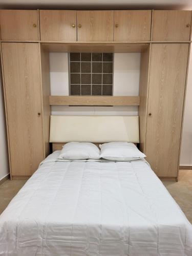 Cette chambre comprend un grand lit blanc et des placards en bois. dans l'établissement Studio haut de gamme, à Nice