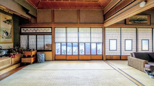 a large room with large windows in a building at スキー場まで15分ー最大10人ーお餅つきー流しそうめんー花火ー五右衛門風呂ー心と身体が元気になる古民家民泊ーオモテナシロッジ悠遊 in Nakafurano