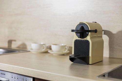 a coffee maker sitting on a kitchen counter with two cups at Escala Hotel & Suites in Budapest