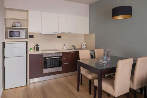 a kitchen with a dining table and a kitchen with white appliances at Escala Hotel & Suites in Budapest