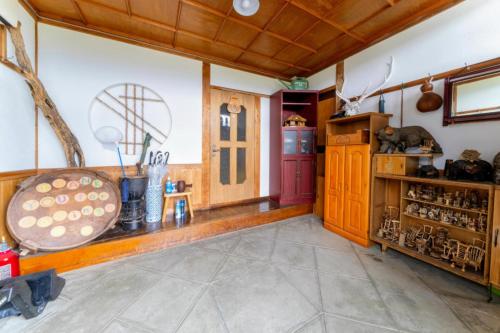 a large room with wooden walls and wooden floors and a room withtainment center at スキー場まで15分ー最大10人ーお餅つきー流しそうめんー花火ー五右衛門風呂ー心と身体が元気になる古民家民泊ーオモテナシロッジ悠遊 in Nakafurano