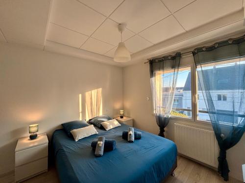 Un dormitorio con una cama azul y una gran ventana. en Villa Des Sables - 50m De La Plage, en Ploemeur