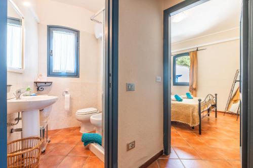 a bathroom with a sink and a toilet and a bedroom at Villa Mare e Monti in Sìnnai