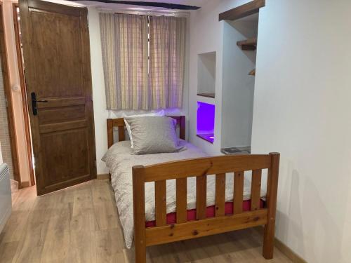 a small bedroom with a bed and a door at Gîte dans maison ardéchoise de caractère in Beaumont