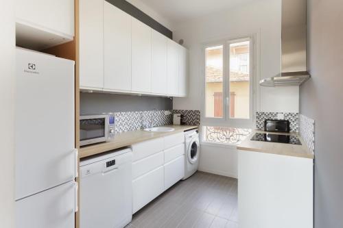 une cuisine avec des armoires blanches et une laveuse et une sécheuse dans l'établissement Bourgeois apartment with sea view, à Nice
