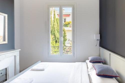 une chambre blanche avec un lit et une fenêtre dans l'établissement Bourgeois apartment with sea view, à Nice
