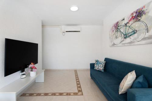 a living room with a blue couch and a tv at Villa Milena in Callao Salvaje