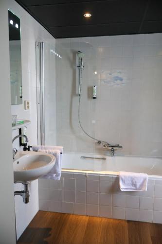 a bathroom with a tub and a sink and a shower at Hotel de Abdij in Horn