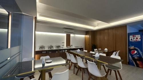 a dining room with a long table and white chairs at Royal Regent Suites Dhaka in Dhaka