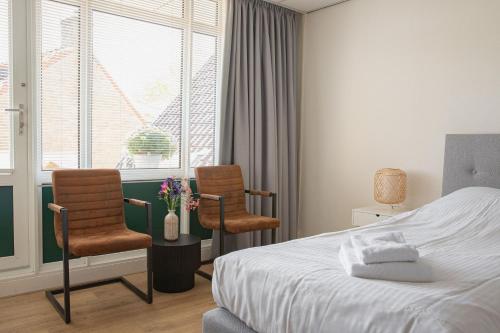 a bedroom with two chairs and a bed and a window at Hotel-Restaurant De Walvisvaarder in Hollum