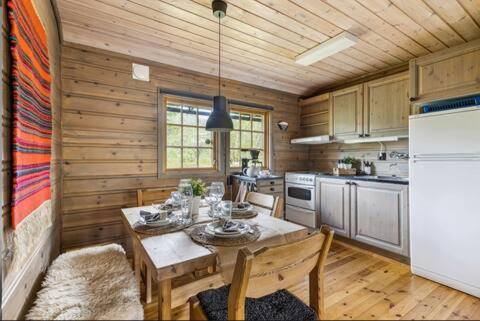 a kitchen with a dining table and a kitchen with a refrigerator at Guest favorite - 5 mins from Vøringsfossen in Garden