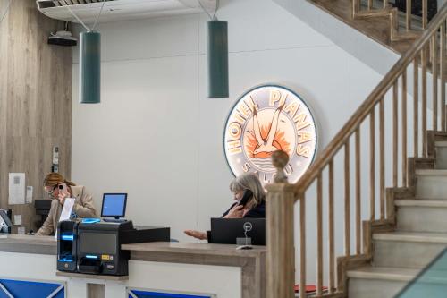 a large clock on the wall and two people at a desk at Hotel Planas in Salou