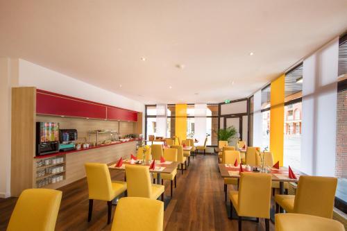a dining room with tables and yellow chairs at Montana Hotel Köln-Bonn Airport in Troisdorf