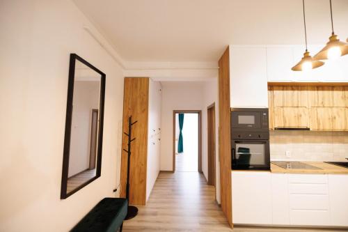 a kitchen with white cabinets and a mirror on the wall at Thyon Apartments in Sebeş