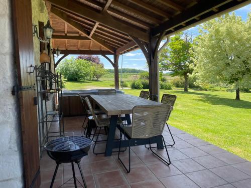 un patio avec une table et des chaises sous une pergola dans l'établissement Gite à la campagne, à Saint-Eutrope-de-Born