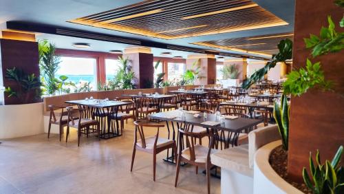 a restaurant with tables and chairs and plants at Alimuri Bay Resort in Meta