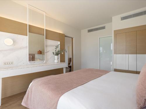 a bedroom with a white bed and a mirror at Avra Imperial Hotel in Kolymvari