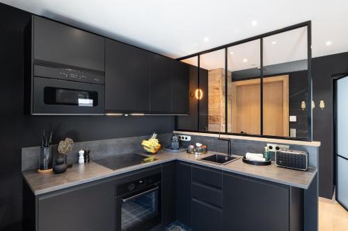 a kitchen with black cabinets and a microwave at Suite Zen By M in Francorchamps