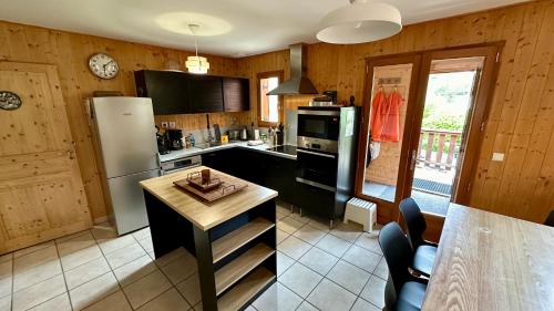 a kitchen with a refrigerator and a table in it at Chalet Le Salers 10pers Le Mont Dore in Mont-Dore