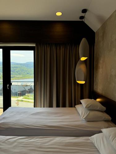 a bedroom with a large bed and a large window at Lake Hill Karkonosze Apartments in Sosnówka