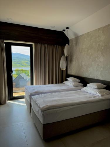 a bedroom with two beds and a large window at Lake Hill Karkonosze Apartments in Sosnówka