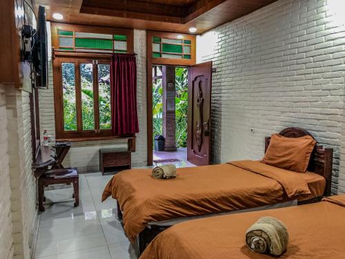 a bedroom with two beds and a brick wall at Arys Garden Hotel Yogyakarta in Yogyakarta